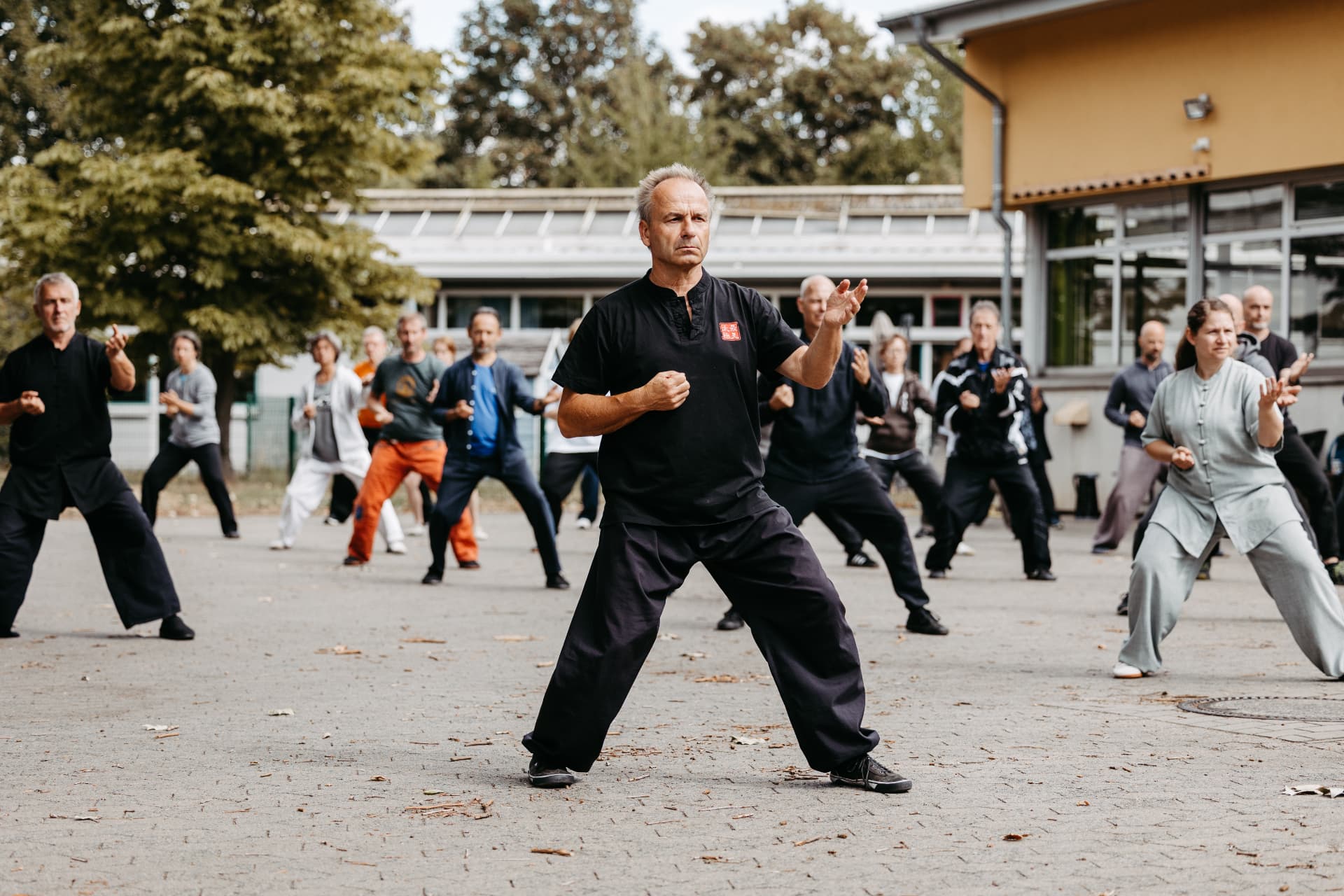 Jochen Köhler übt die Kompaktform im Freien, dahinter eine Gruppe von Übenden